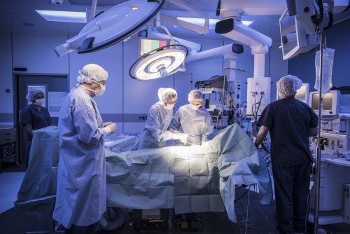 Four doctors in hospital operating room with patient lying on operating table. Visual concept for a legal blog discussing the Ohio Defective Product Law and Defective Medical Devices.