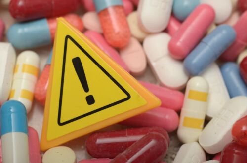 Multi colored pills and a caution sign. Visual concept for a medical malpractice blog discussing medication errors.
