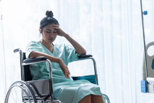 Serious patient sitting on wheelchair in hospital.